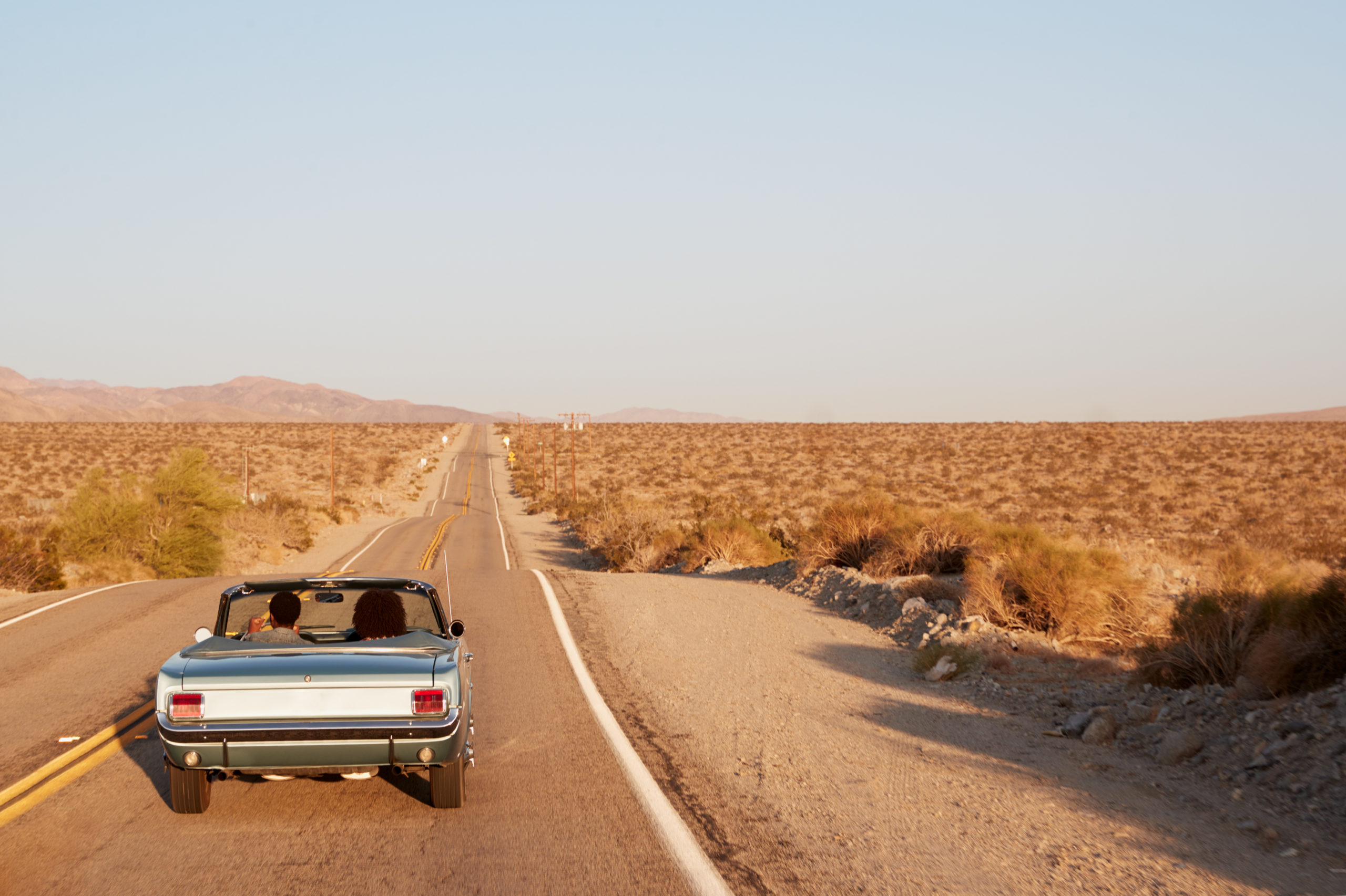 Couple taking a road trip through the desert in a convertible